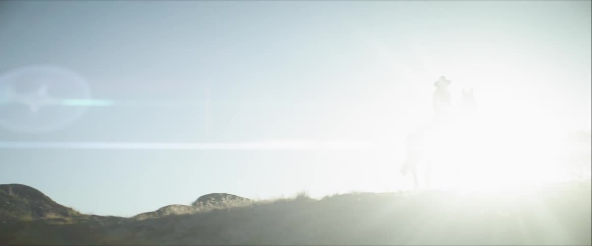 A person wearing a cowboy hat rides a horse in the early morning