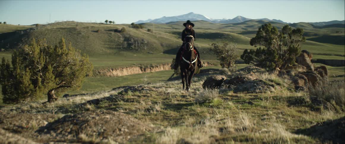 A woman rides her horse across a field