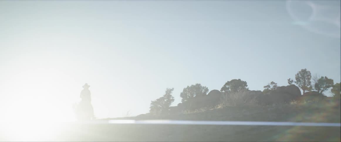 A person riding a horse with the sun in the background