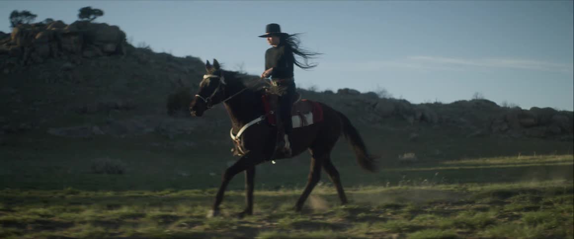 A woman riding a horse as it gallops through a field