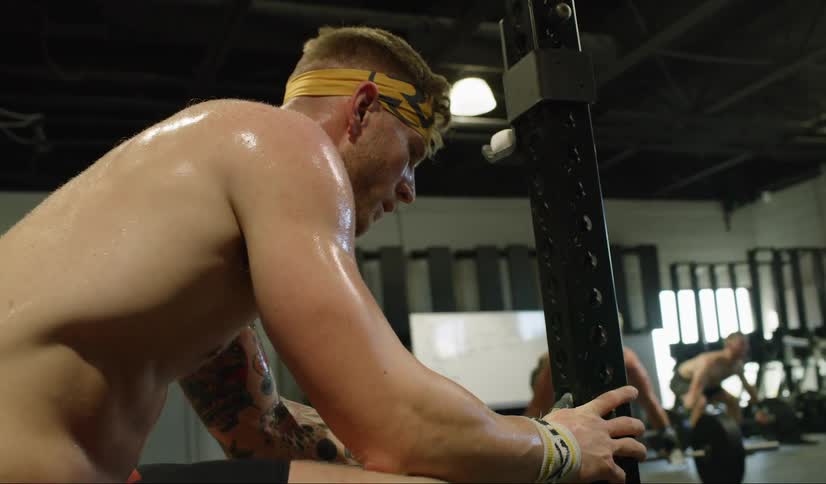 A man sits on a piece of athletic equipment breathing heavy from exhaustion