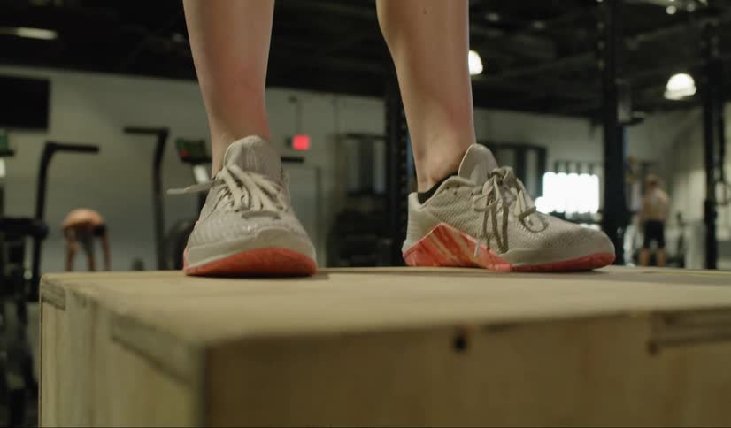 A woman does box jumps in a gym