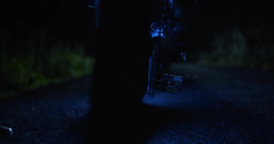 Led lights around bicycle tires glow on a path at night