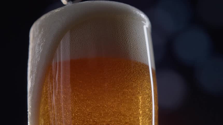 A glass of beer with foam spilling over the edge