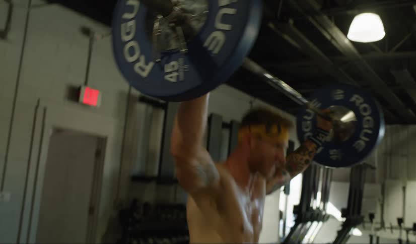 A man in a indoor gym lifting weights above his head then throwing it to the ground
