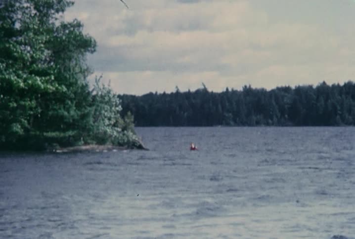 Person waves while floating in the water in a lake