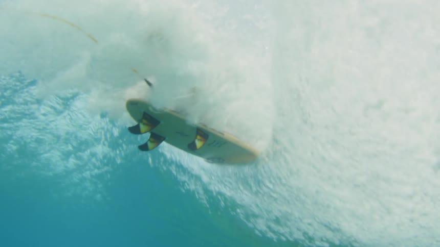 Short surfboard passes overhead on surface of the water