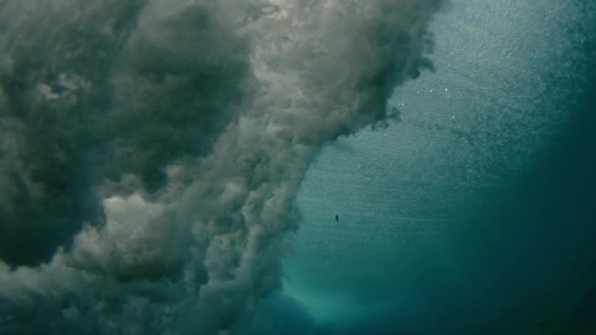 over under shot of a wave crashing over lens of camera