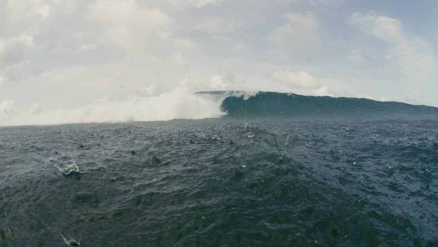 A large wave rises and then barrels over to collapse into the surface of the ocean