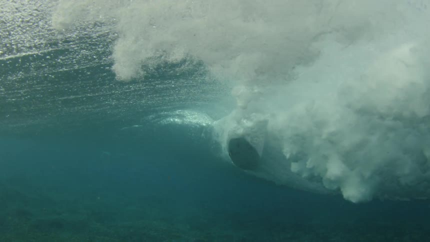 Underwater footage of surfboard riding a wave