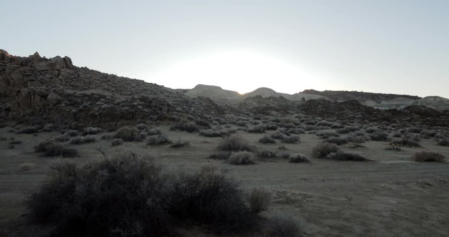 Dirt road cuts through scrub rocky hills and sand in desert