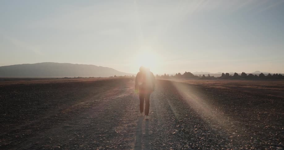 Person walks along gravel road near mountain