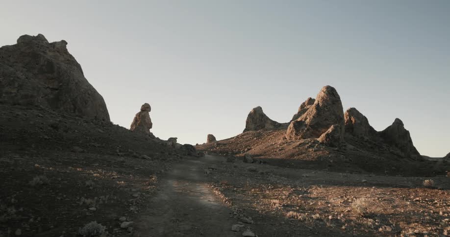 Rocks and boulder surround a narrow path through desert at sunset
