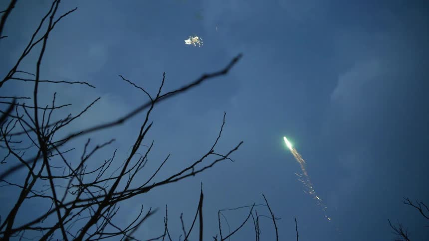 Under a cloudy sky a number of small fireworks are launched upwards into the sky