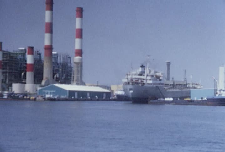 A large ship is docked by the shore on a sunny day