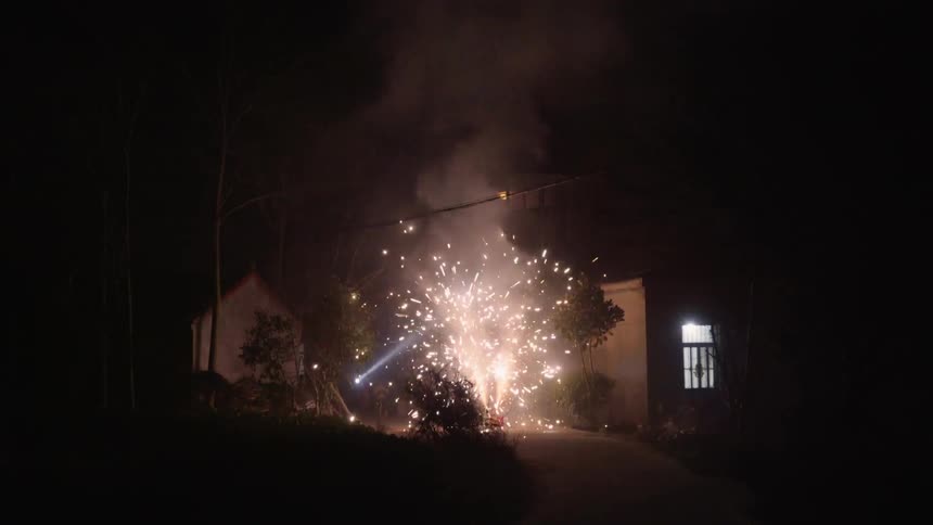 Fireworks going off at night in a driveway with a house in the background