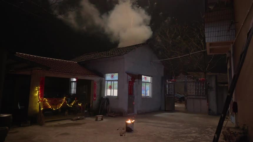 Fireworks shoot up toward sky from behind building at night