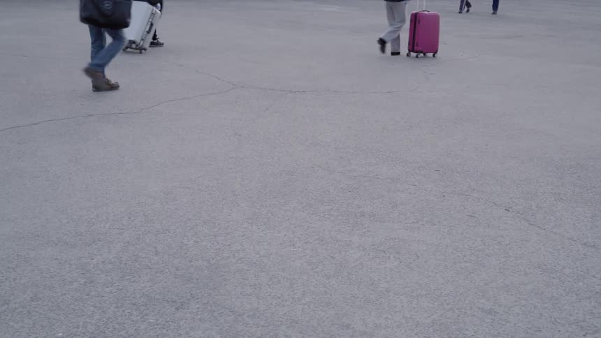 People walking and carrying and pushing or pulling luggage with them