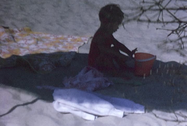 A child playing with a bucket on the beach