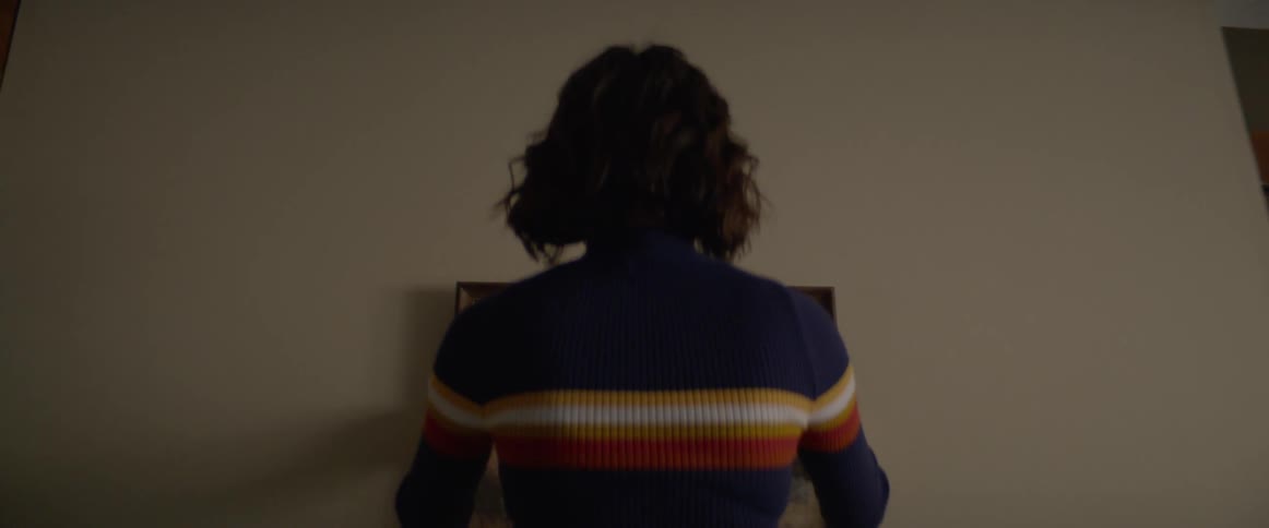 A woman adjusting a picture frame on a wall