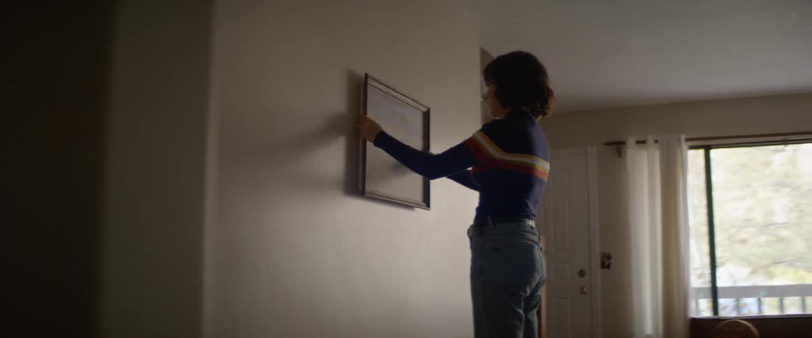 Woman adjusts alignment of frame on wall
