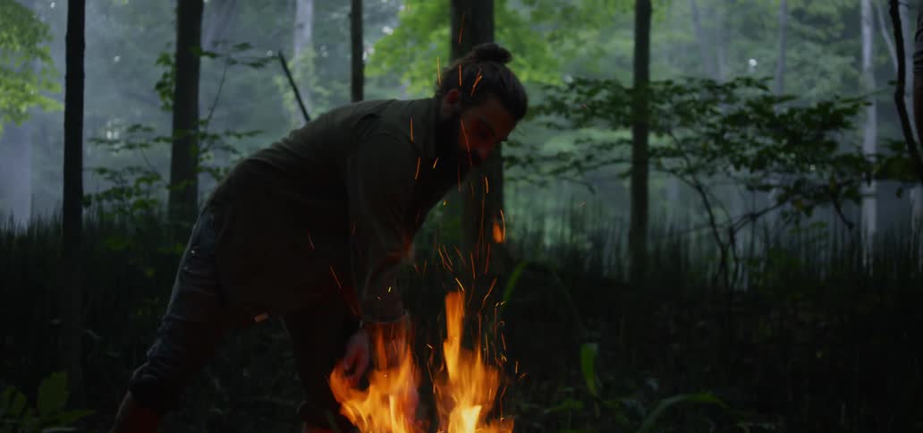 A man puts sticks on his burning fire
