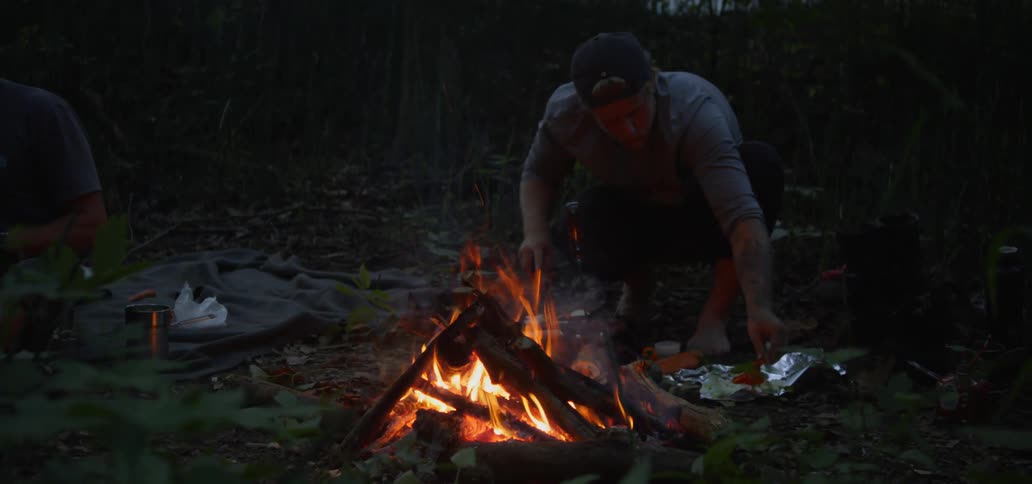 Man cooks over campfire in forest