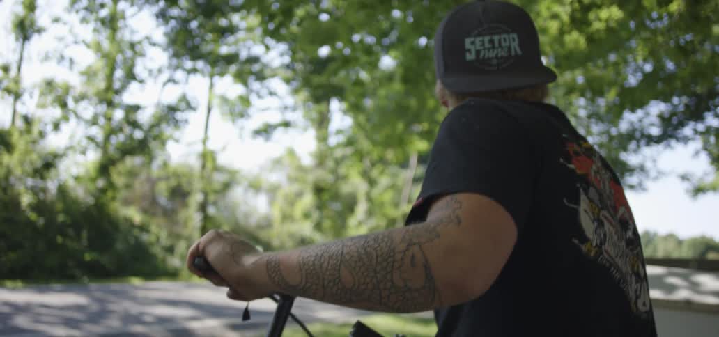 A man sitting on a bike looks left and right on a road on a sunny day