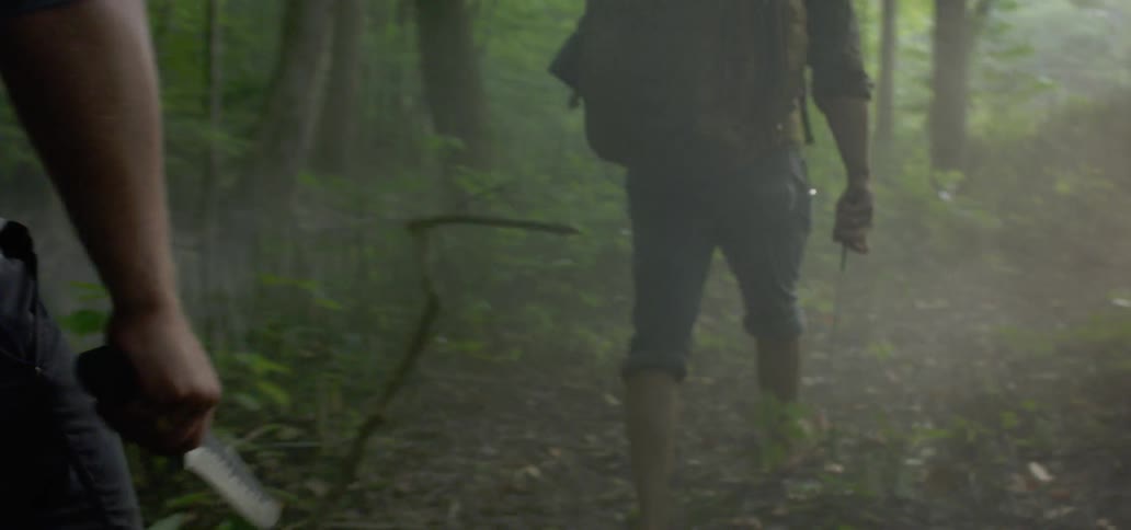 Men aggressively walking through forest carrying weapons