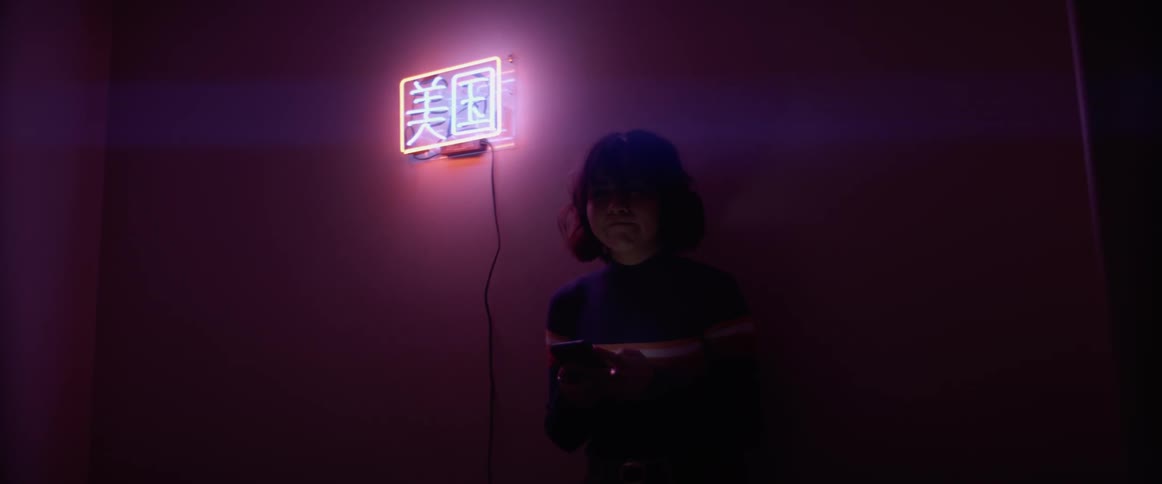 A woman is leaning against the wall in a dark room