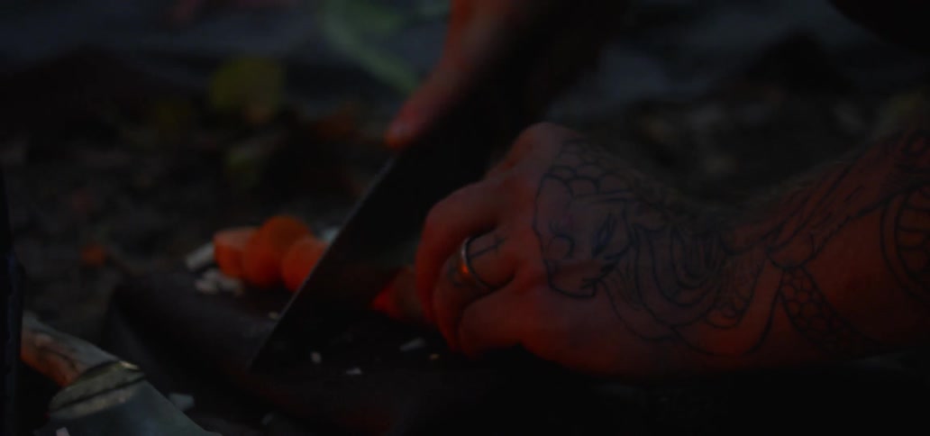 A persons hand chopping up a carrot with a knife