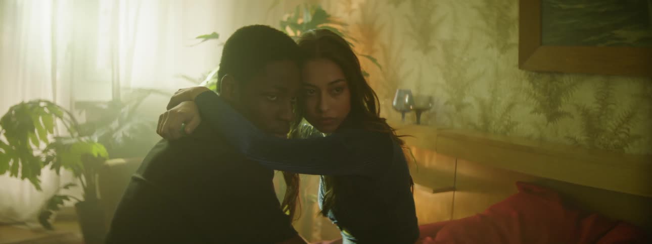 A woman has her arms around a mans neck while sitting and looking as if having a photo taken