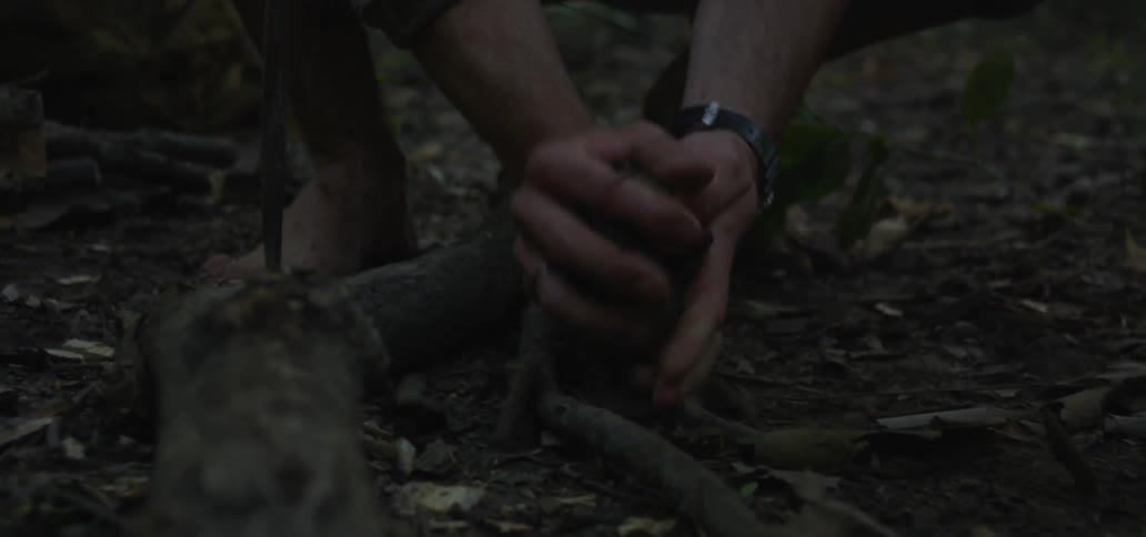 A person gathers sticks on the ground