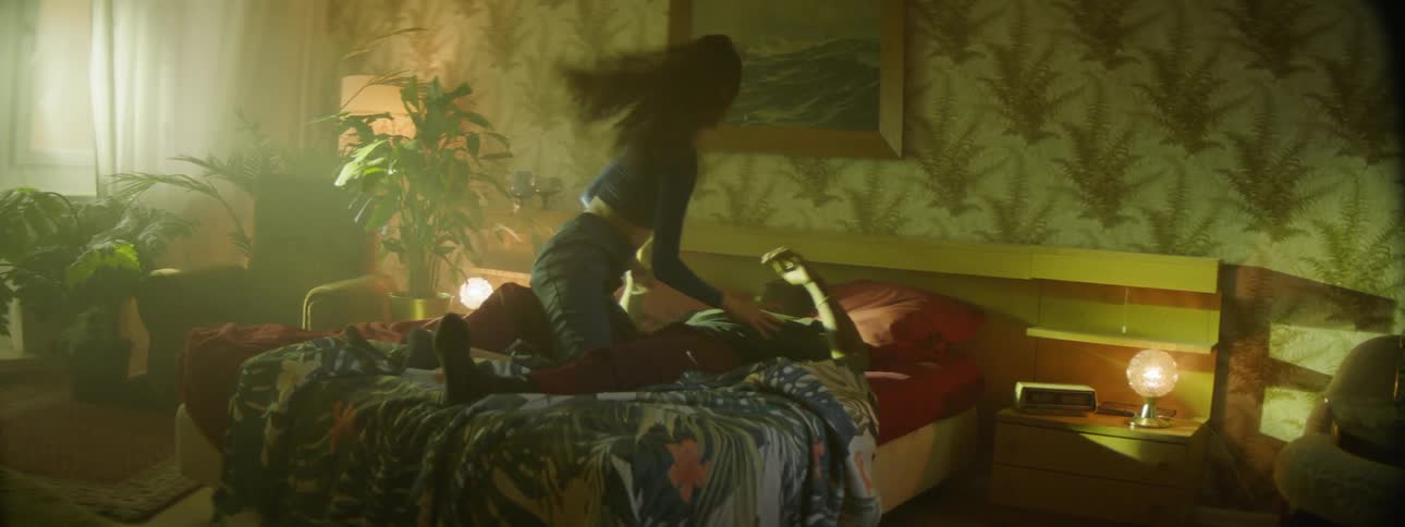 A man and woman play wrestle on a bed together romantically