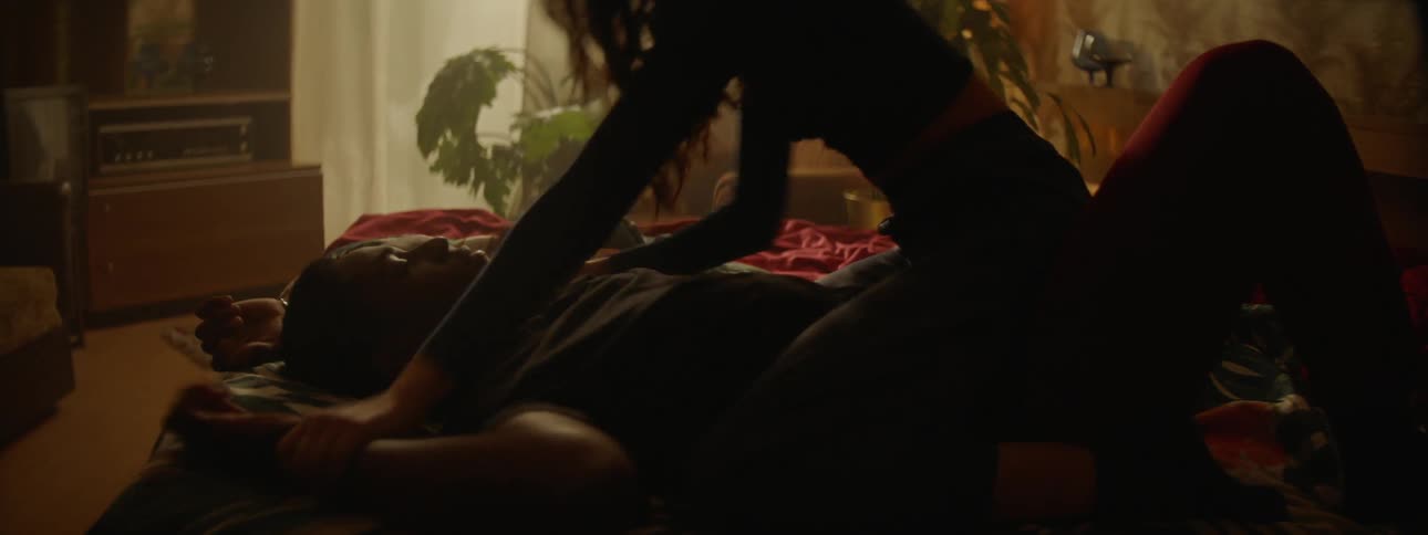A woman straddles on top of a man laying on a bed