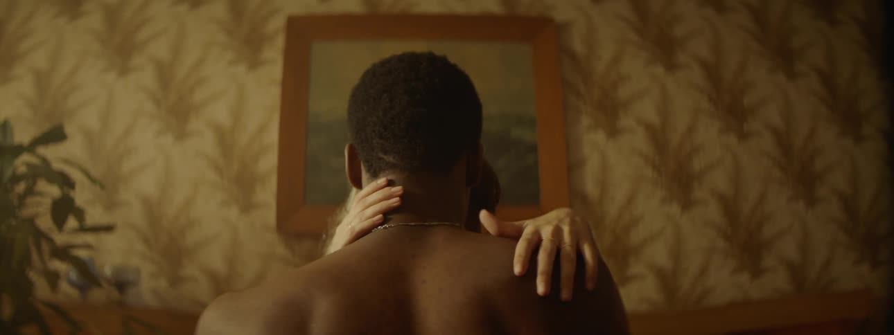 Shirtless couple kisses on bedroom