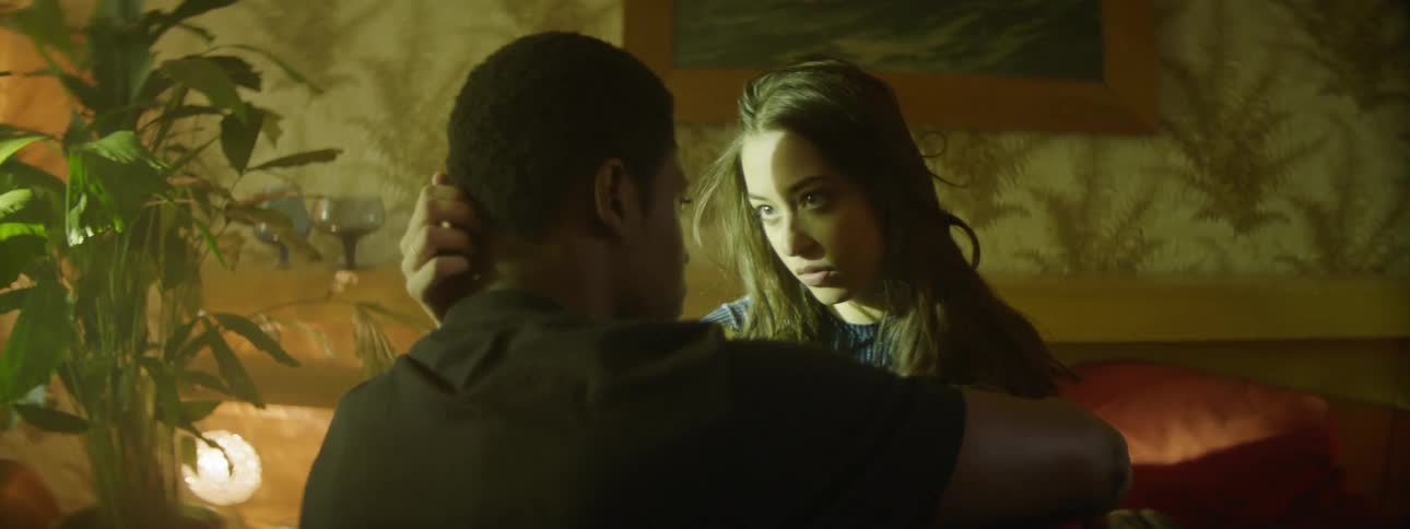 A man and a woman sitting on a bed caressing each other