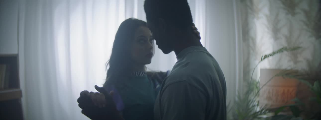 Couple dances slowly on a dim lit room