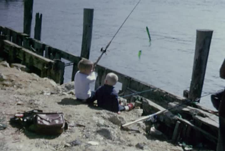 Two boys fish off of a pier