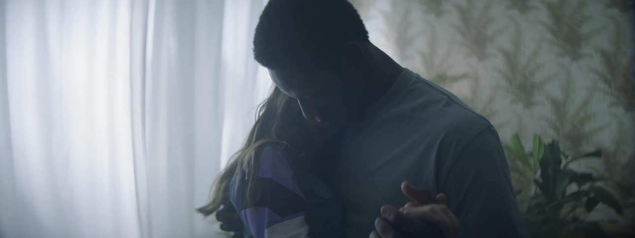A man and woman dance inside a room