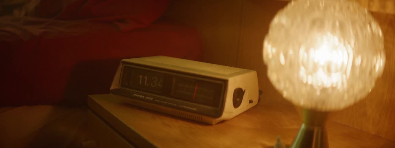 An alarm clock and light on a bedside table