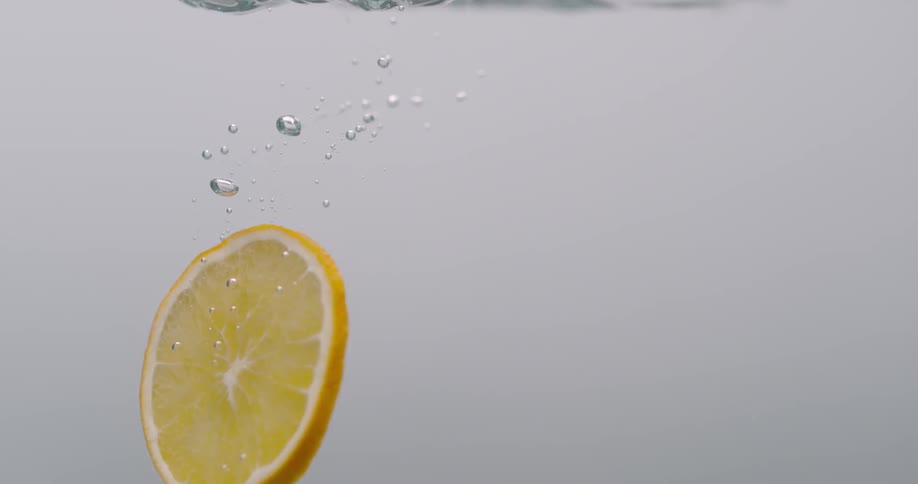 Orange slice falling down the water