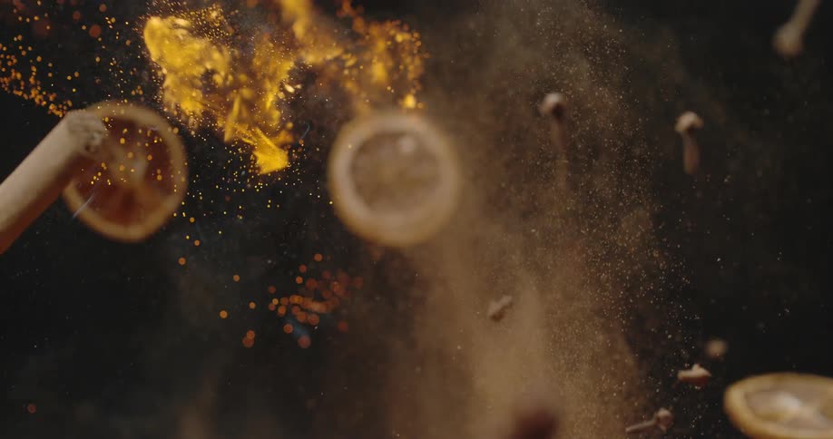 Spices and lemon slices fly in the air with smoke and flames in the background