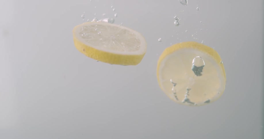 Two thin slices of lemon plunge down into crystal clear water