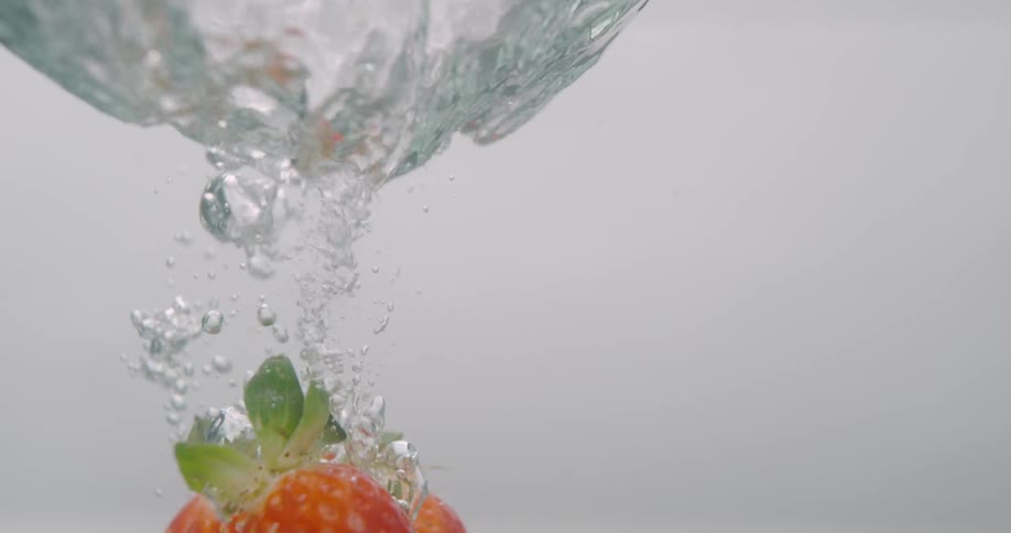 Strawberries falling down the water