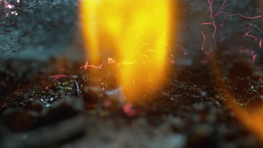 Flames rise from hot embers on the ground