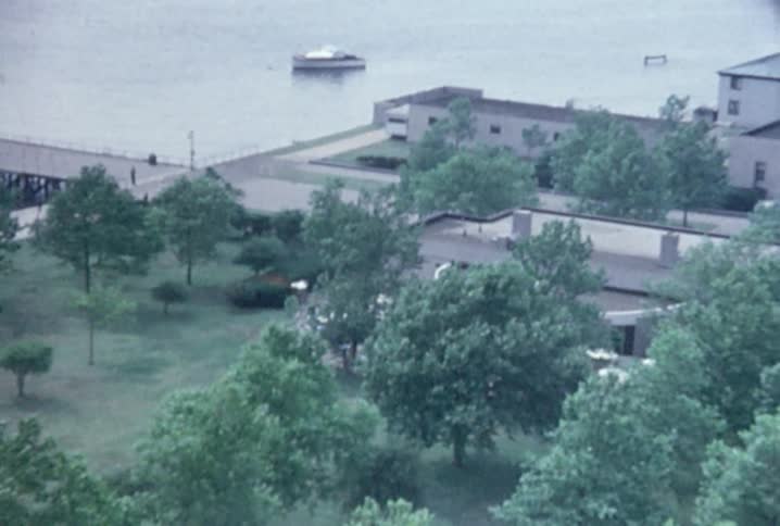 A sightseeing ferry is at the dock as people walk around liberty island