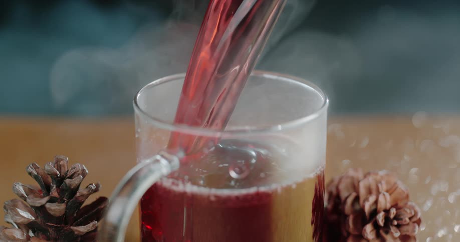 A beverage is being poured in to a glass mug