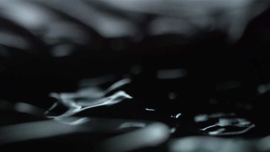 Dark liquid with floating items reflecting the light