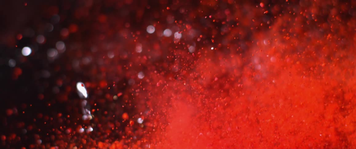 Red flakes tossed into the air against dark red sparkling background